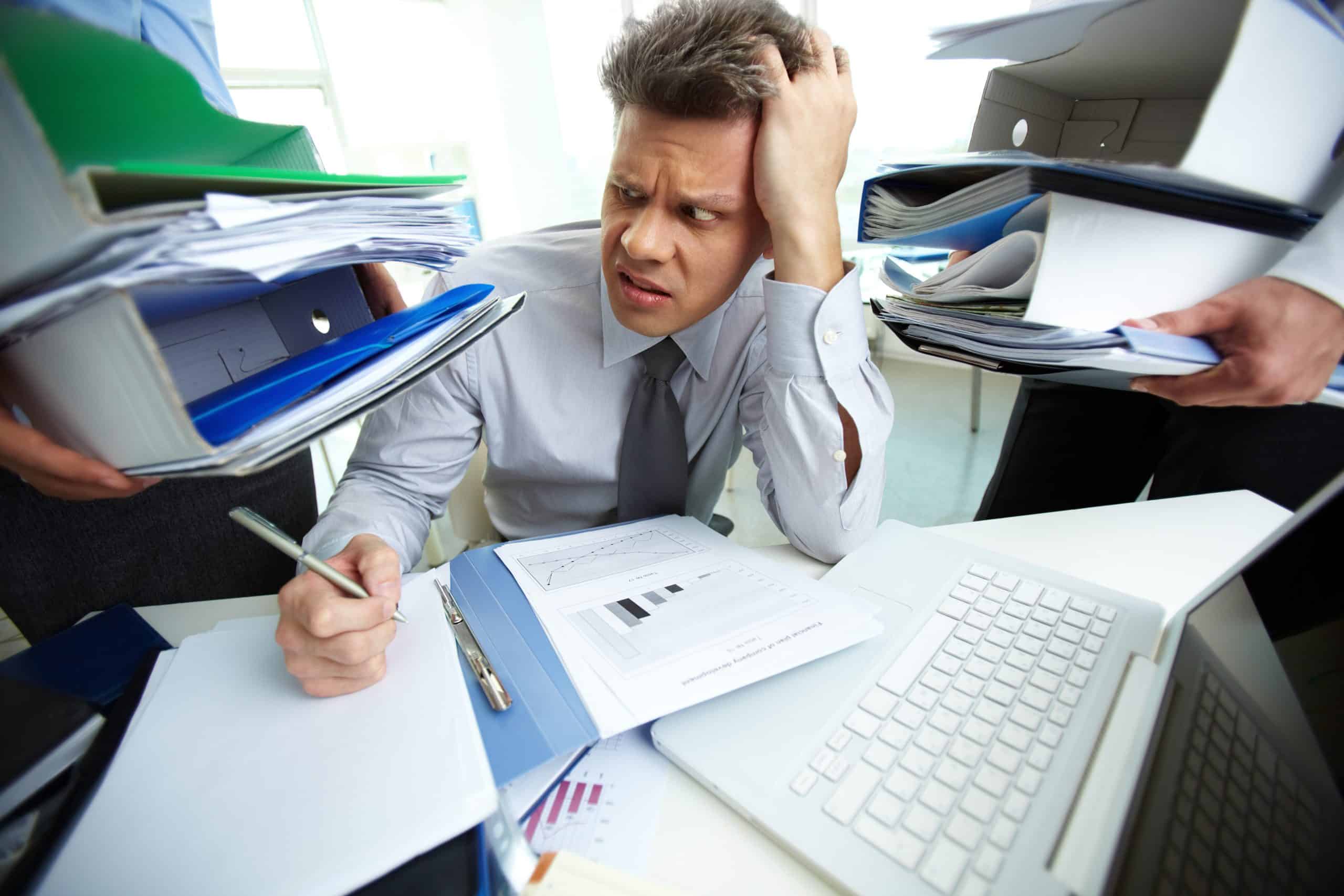 Finance medewerker zit vermoeid achter bureau met volle inbox en documenten| Finnt