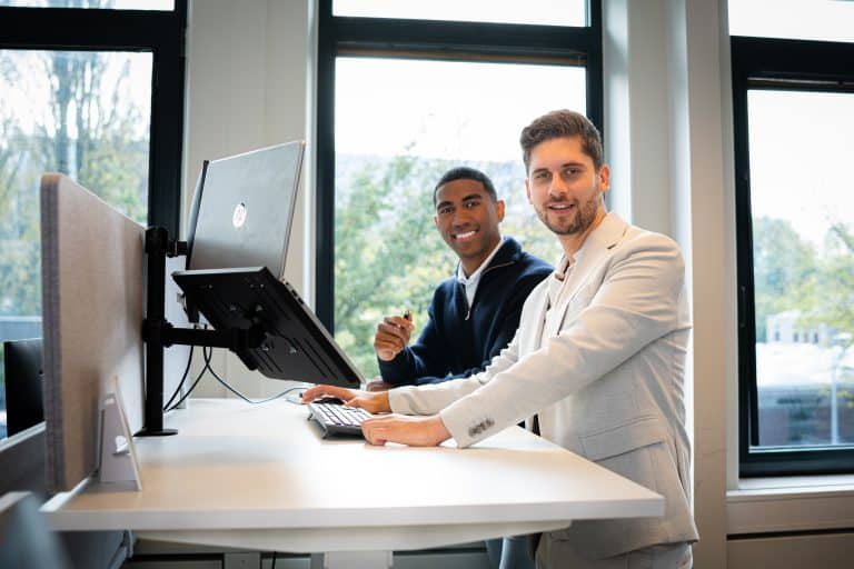 Twee finance professionals werken samen achter een monitor op kantoor