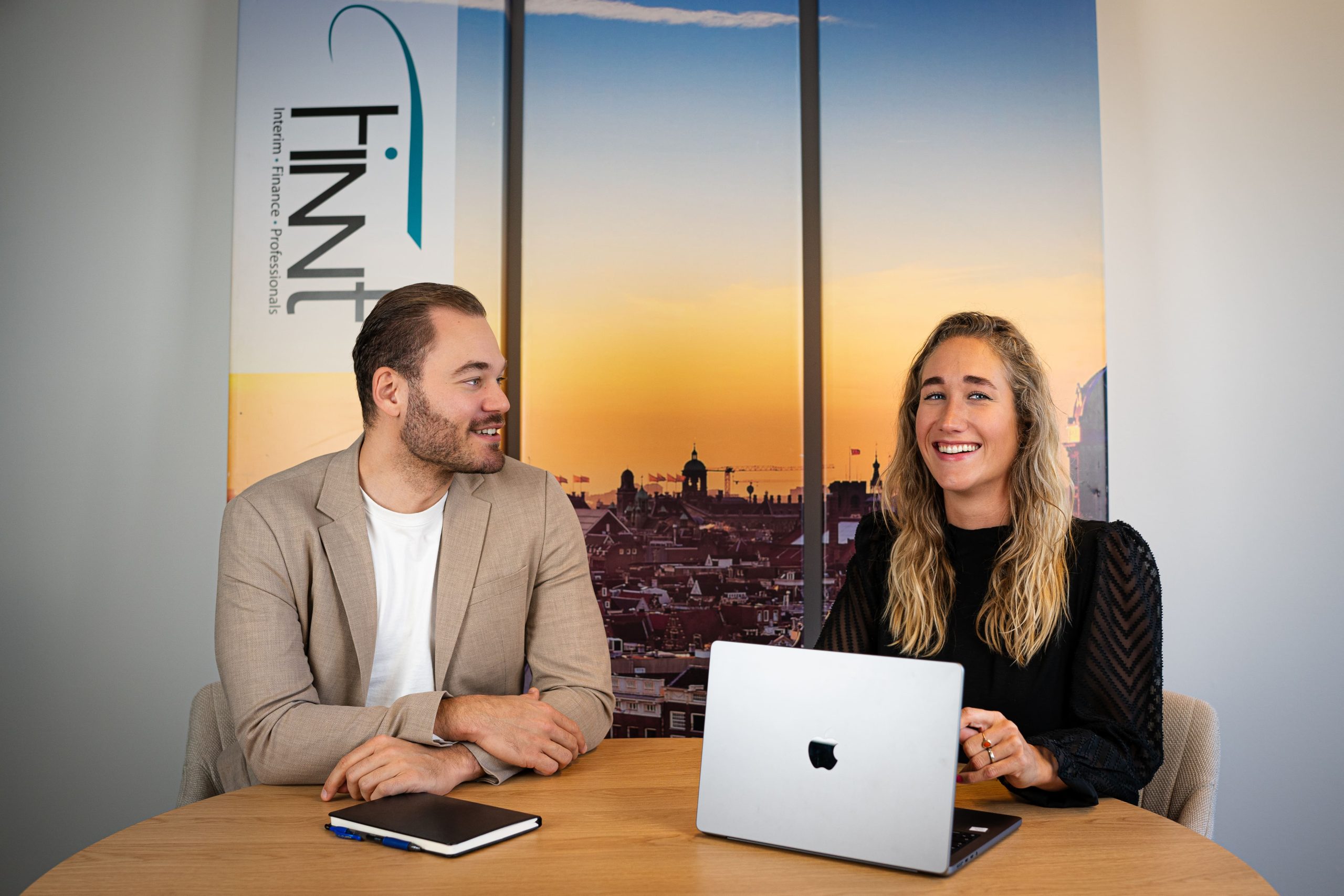 Twee recruiters van Finnt in gesprek aan tafel voor een Finnt-banner